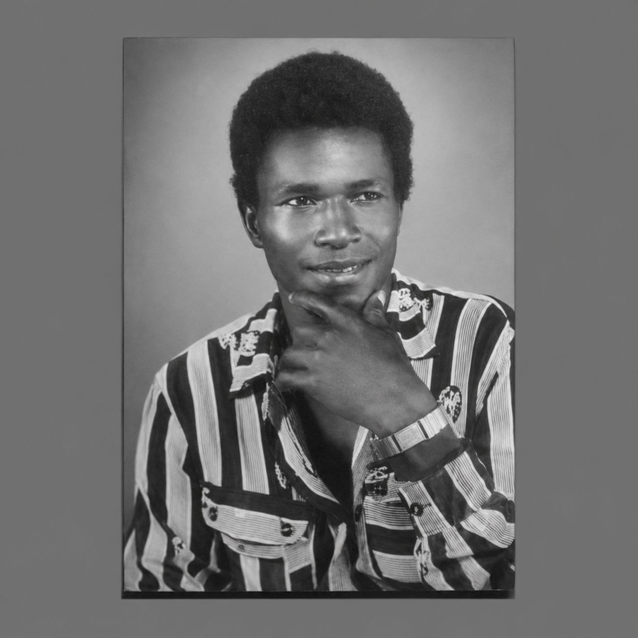 Black and white studio portrait of Chief Echo Toikumoh wearing a striped shirt